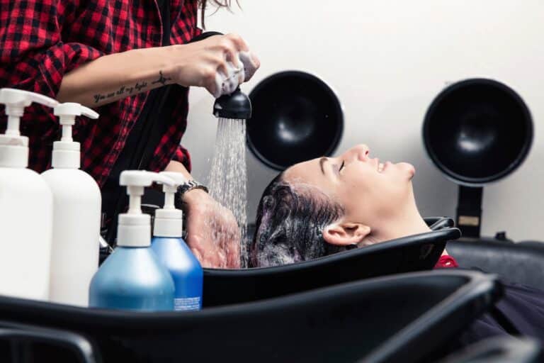 Shampoo girl rinsing customer's hair in salon